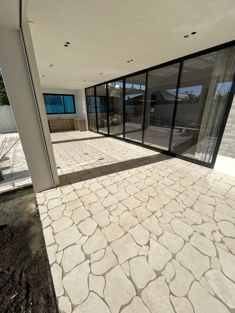 Crazy-paving stone patio extending to glass-walled living area