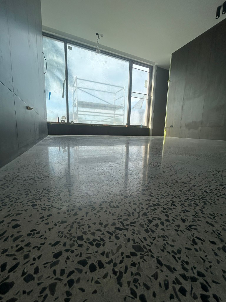 Mirror-polished concrete floor with grey and black aggregate in modern home