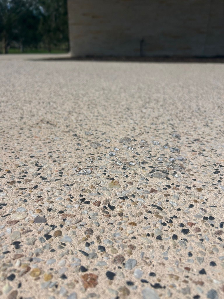 Macro shot of water beading on freshly sealed exposed-aggregate concrete