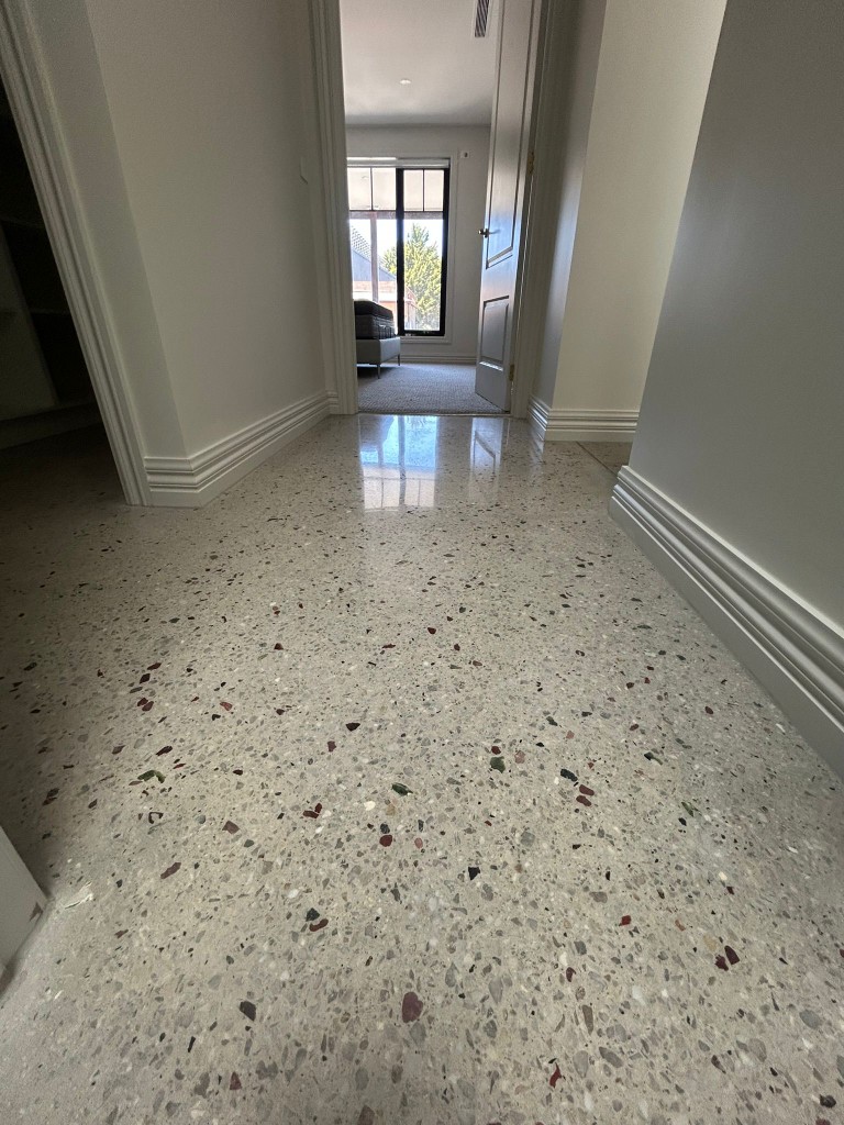 Heritage polished terrazzo hallway with densely packed marble chips and white skirting