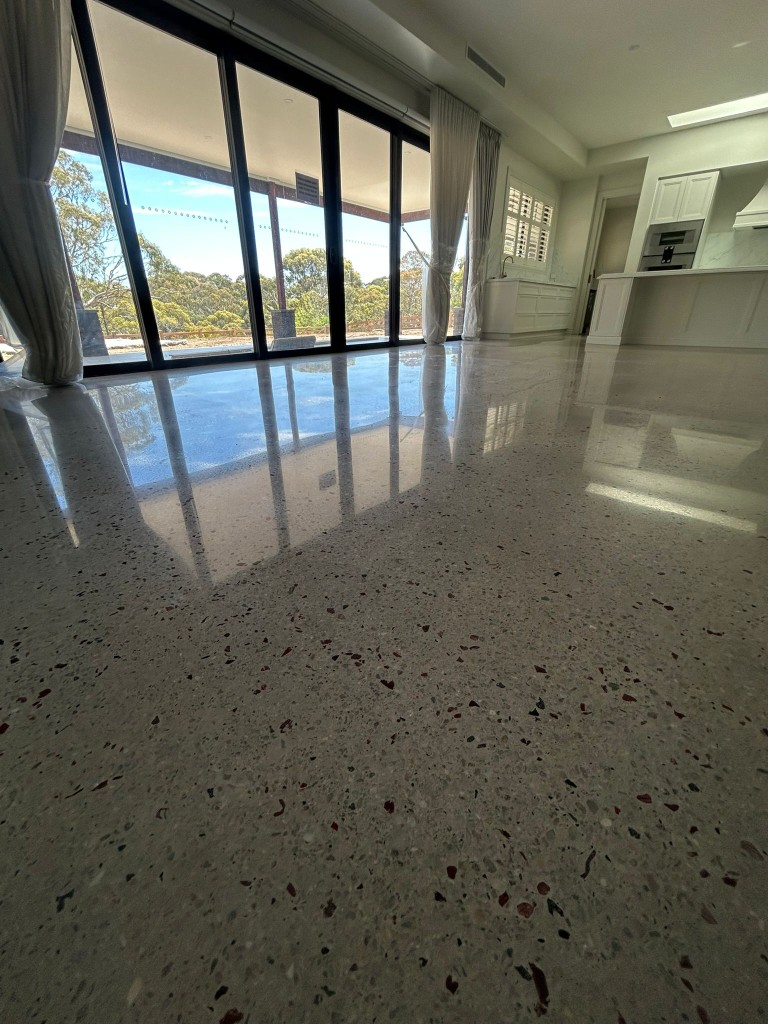 Mirror-polished concrete floor with red and black exposed aggregate in modern kitchen