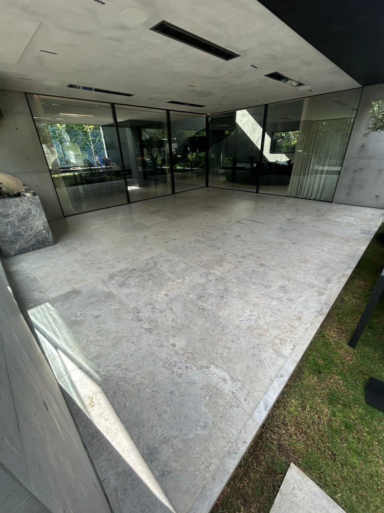 Honed limestone paving at modern concrete-clad luxury home