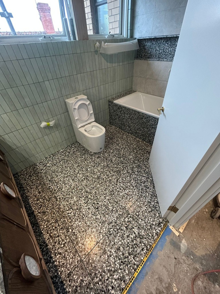 Restored heritage terrazzo bathroom with vintage tile and bath