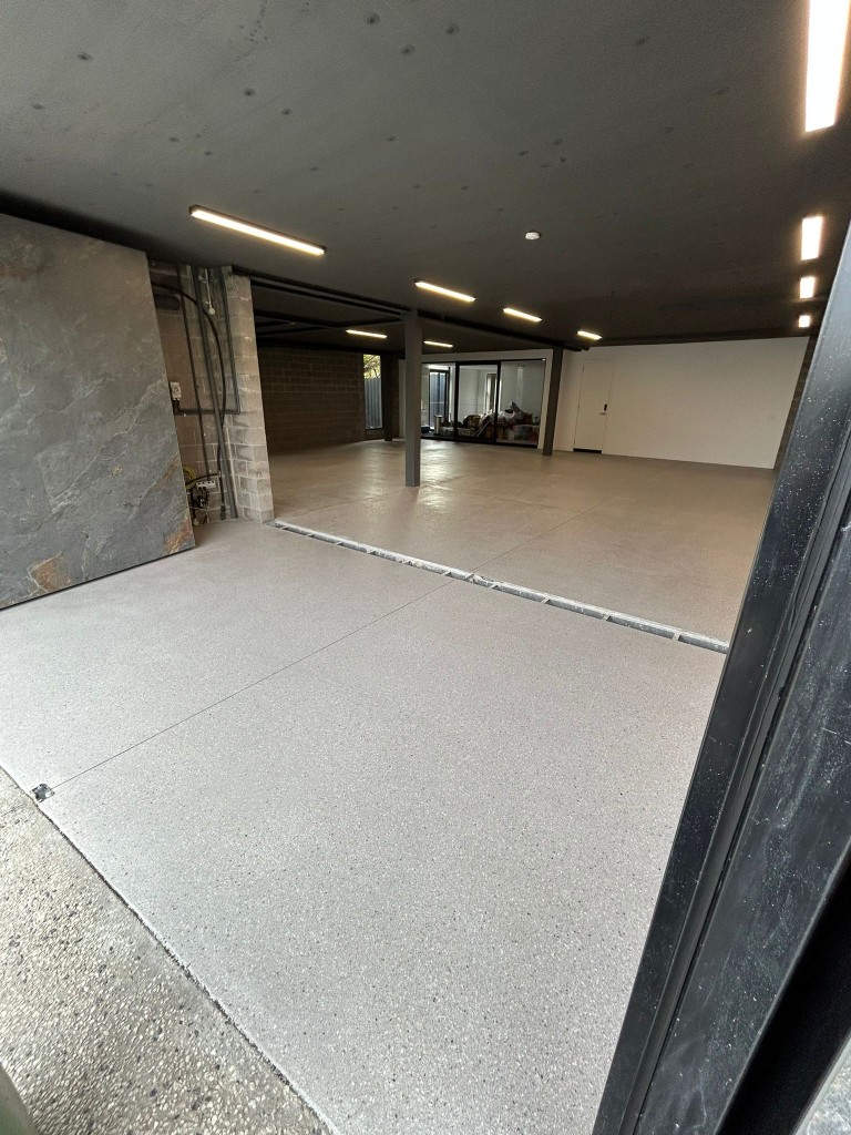 Light grey epoxy garage floor with stone feature wall