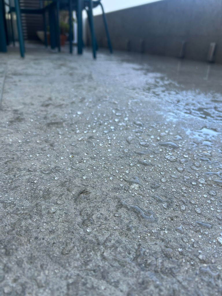 Macro shot of water beading on freshly sealed exposed-aggregate poolside